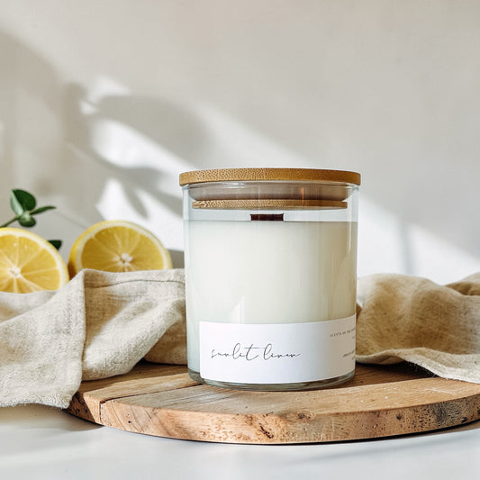 Linen and lemon scented coconut wax candle in glass jar on wood round